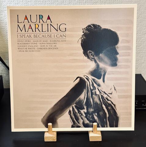 Photo of a record album jacket. The jacket has a black and white photo of a woman, half-hid in shadow, her hair tied up, her right hand pressed into the small of her back. 

In the top left hand corner, black type reads, ‘Laura Marling, I Speak Because I Can.