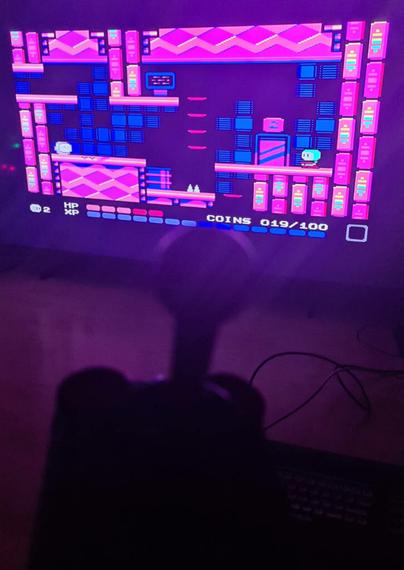 A Commodore 64, a joystick and a screen showing level 2 of the 2023 game Lester.
The player only has 2 lives left, and the health bar is 40% depleted.