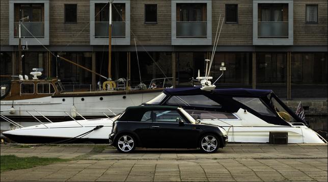 A soft-topped Mini car in front of a soft topped boat at the quayside. The point is the coincidence.  It is possible that the owner of the car is also the owner of the boat.