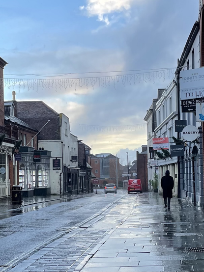 Jewry street in Winchester. Just had a heavy downpour and a lone man walks along the street with his up on a Sunday morning.