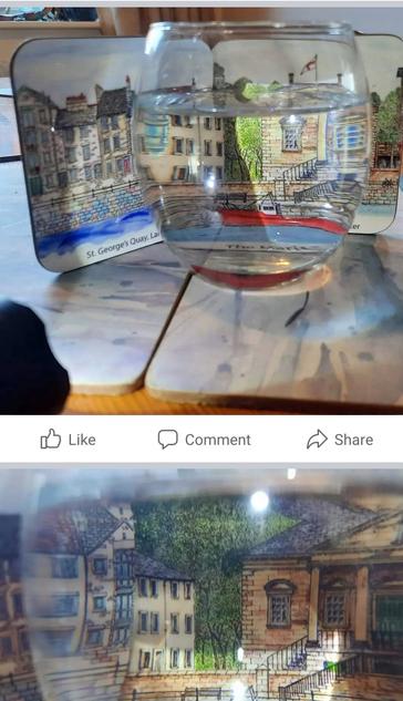 A coaster of a drawing of a city - Lancaster - seen through a glass of water.