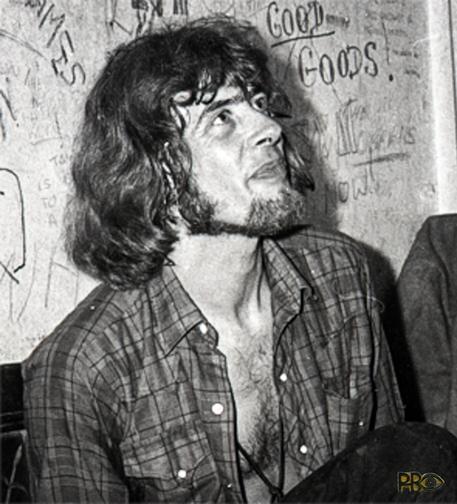 Bearded, longhaired John Mayall from the Bluesbrakers 1960s sitting back Stage at The Marquee Club in London during a break, looking upwards - shirt unbuttoned.