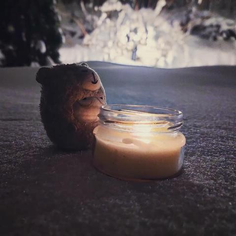 Photo of Pepyaka sitting with a candle in the dark, snowy landscape.