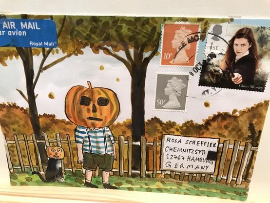 Ein kleiner Junge mit gestreiftem T-Shirt vor herbstlicher Lamdschaft. Er hat einen Halloween-Kürbis über dem Kopf. Die kleine Katze links von ihm auch. Auf der Briefmarke ist Hermine aus Harry Potter.