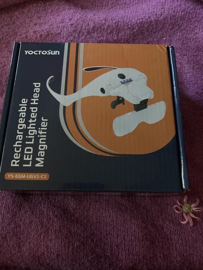 Black and orange box containing Rechargeable Lighted Head  LED Magnifier