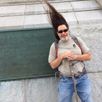 A man standing in front of New Jersey's Highpoint Monument, and the "breeze" has taken his long hair, and has it standing straight up, over his head