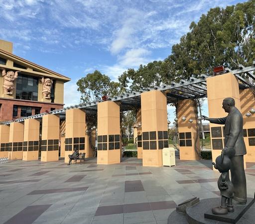 Walt Disney statue pointing at trash can