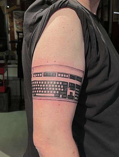 Ein Oberarm mit einem frisch gestochenen Tattoo, das Motiv ist eine IBM Model M Tastatur.