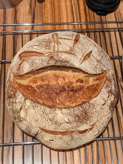 Brot von oben, rund, in der Mitte aufgerissen, Schnitte formen ein breit grinsendes Gesicht