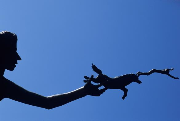 A rich blue sky. The silhouette of an androgenous head and arm extended from the left side. Leaping from the hand is a horse. Leaping from the horse's head is a person diving into... open space