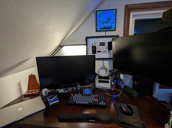 An image of a desk with two large monitors, a MacBook pro, a keyboard, a mouse, and a stream deck