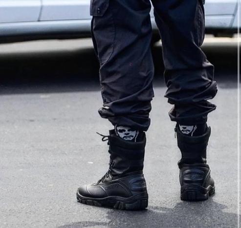 [ID: A photo showing a military policeman’s boots. He’s wearing socks with Jair Bolsonaro’s face on them. End ID]