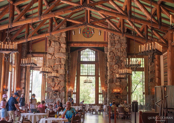 Awhawnee dining room during the pandemic. Massive space with cathedral ceiling, wooden beams, stone pillars, huge windows and giant chandeliers. People mill about, some with masks, waiting for their box lunches to take outside.