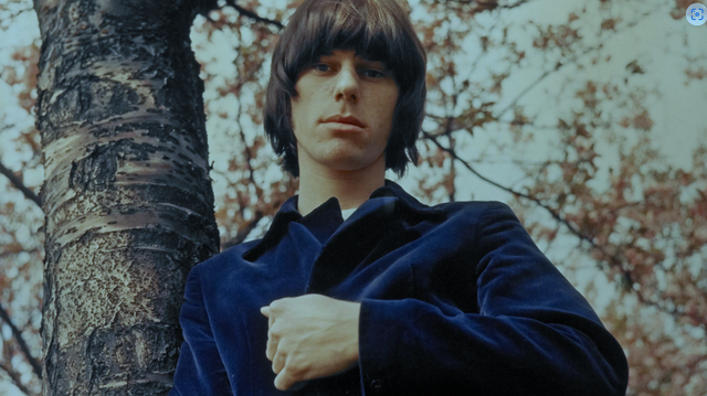 A young Jeff Beck stares down at the camera from a stand of trees.