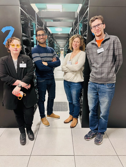 Four scientists standing in front of back of Aurora racks