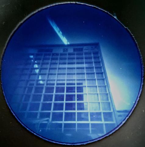 A hotel high-rise, with the sun's track passing over it. The track is reflected back on the hotel half way up. There are some partial gaps in the sun's path where cloud has covered it.