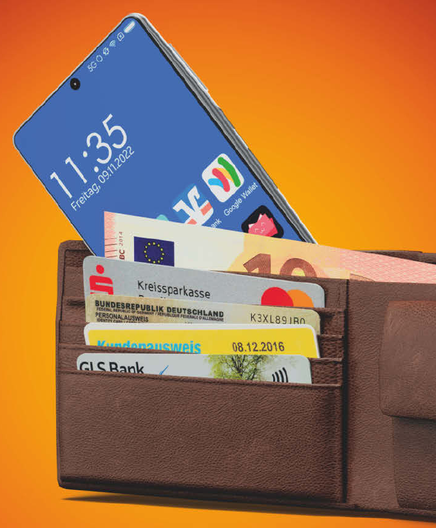A photo of a wallet with several loyalty cards with a smartphone peeking out. In the bottom right of the home screen's app list the app icon for Catima is visible (the app name is obstructed by the wallet itself).