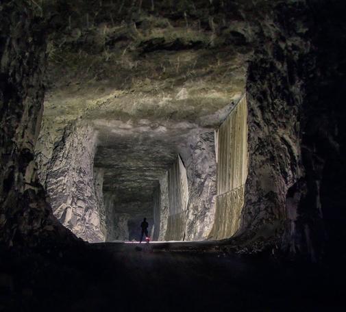 Photograph of a tiny section of the absolutely immense Middleton Mine deep beneath a small town in Derbyshire. 

Middleton is a #LimestoneMine noted for it's high quality limestone which when polished was used for monuments, and headstones during the wartime. A lot of the war graves were made from the extracted limestone. 

The photograph shows one of the roadways between massive rock pillars which hold up the roof of the tunnels, these roads are some 11m wide by 8-10m high and there are over 25 miles of them down there.

An exploring buddy has been running up and down a length of tunnel madly waving a torch around to paint the scene with light, a flash from a camera wouldn't even register. Once he stood still the camera picks him up so you see a tiny figure in a huge lit tunnel.
