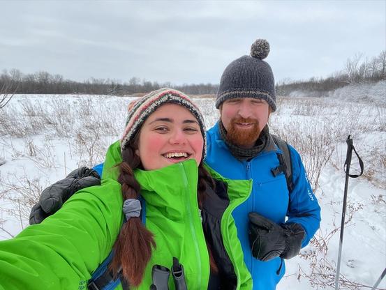 Dans un champs couvert de neige, Gersande et Leif donnent de grands sourires à la caméra (tellement bien que Leif a les yeux mi-fermés!)