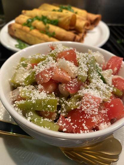 Prickly pear salad set in the bowl, with extra taquitos in the background