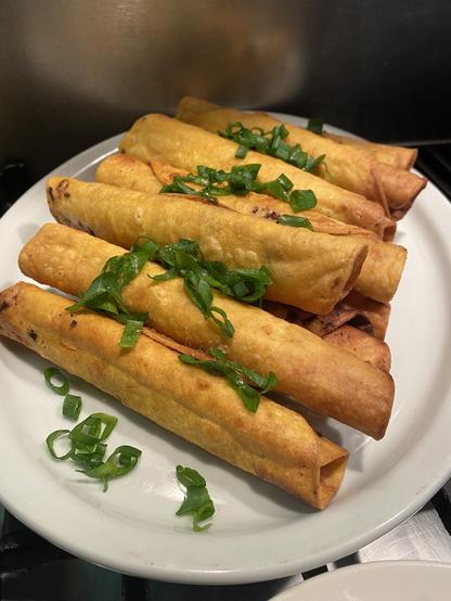 Extra taquitos on the plate garnished with sliced green onions