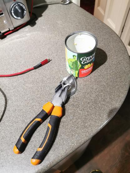 Pliers with an an open ring pull can and lid on a kitchen counter