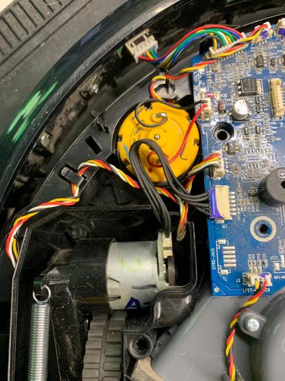 Image of the inside of a vaccum bot with exposed wires and a motor.