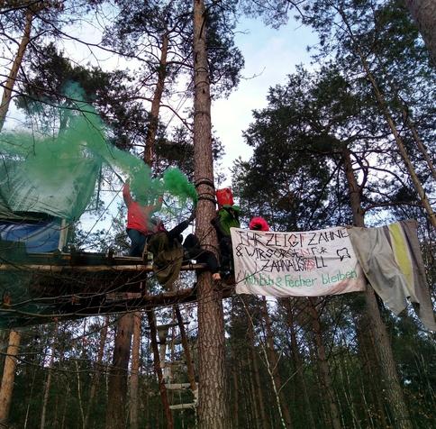 Bildbeschreibung
auf dem Bild ist ein Transpi zu sehen mit der Aufschrift: 'Ihr zeigt Zähne & wir sorgen für Zahnausfall. Alti, Eichi & Fecher bleiben!' Daneben hängen Leute in einer Traverse und auf einer Plattform wird grünes Pyro gezündet.
