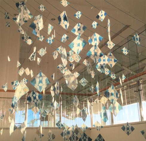 hung installation of blue and white geometrically patterned square images. 500 of them are hung in a double helix pattern