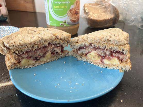 A peanut butter, jelly and banana sandwich on a plate. It’s thick and looks yummy.