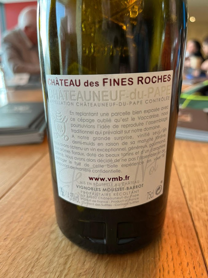 Photo of the back label of a bottle of Châteauneuf-du-Pape by Château des Fines Roches. A paragraph in French explains how the wine is made from the "forgotten variety" Vaccarèse.