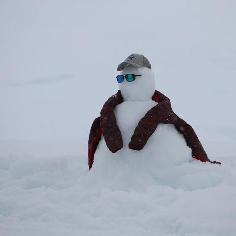 Schneemann mit Baseballmütze, Sonnenbrille und umgehängter Winterjacke