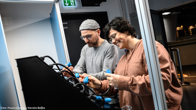 Zwei Personen an einem Exponat der Power2Change-Ausstellung.