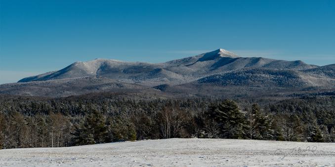 Mountains with trees and snow in foreground.