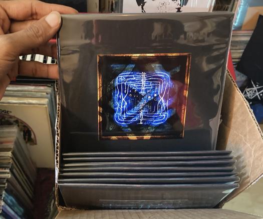 Showing the completed project. A hand holding one record pulled from a box of sleeved 7 inch records