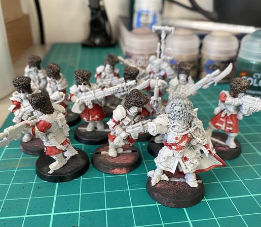 Cutting table with a squad of Vostroyan Miniatures on it. They are in the process of getting base coats of paint.