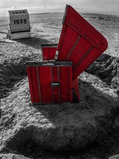Schwarz Weiß Aufnahme von 2 Strandkörben, von denen einer rot eingefärbt ist