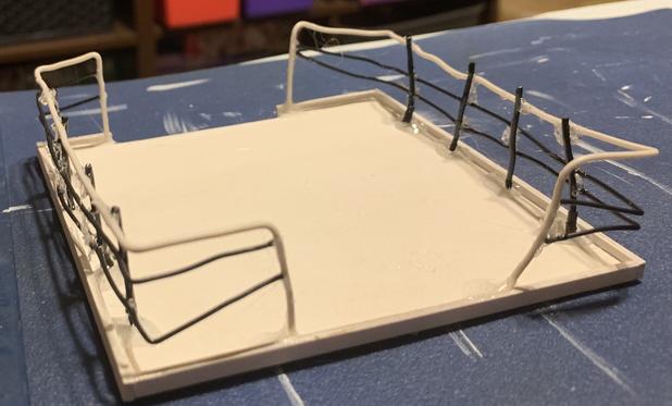 White square loft platform with horribly misshapen black and white wire railings on 2 sides that wrapped around corners leaving openings in the middle of the other two sides.