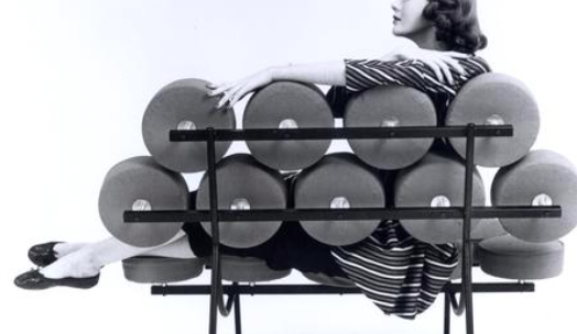 Woman lounging on a Modernist 'marshmallow' chair and looking to the side, seen from the back of the chair with only parts of her visible