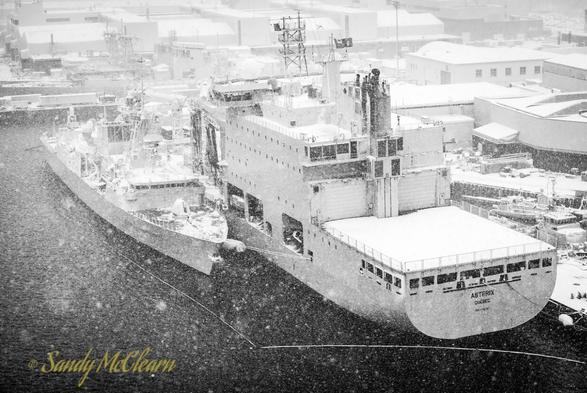 Frigate and replenishment ship alongside in a snow storm.