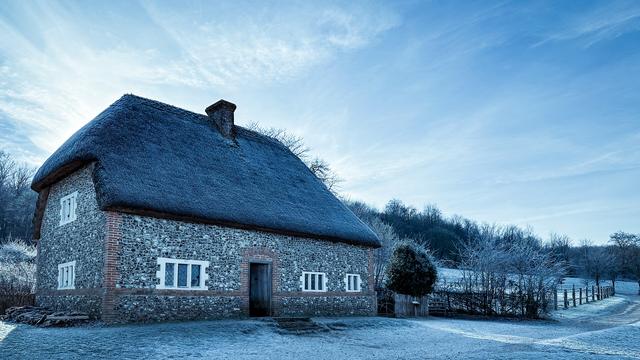 A Victorian era cottage with flint walls and thatched roof on a cold and frosty morning at Weald and Downland Living Museum near Goodwood, West Sussex.