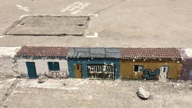 streetart on the curb of a street: painted  three houses on the side of the curb