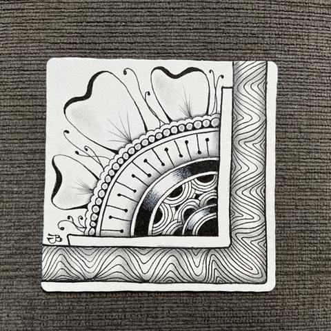 A close up of a piece of Zentangle art. It’s been made on a 3.5 by 3.5 inch white Zentangle paper pile, with black Sakura ink and graphite shading. A large border runs along the bottom and up the right side. Several semi circular bands radiate from the inner corner. Three leaves grown from the bands.