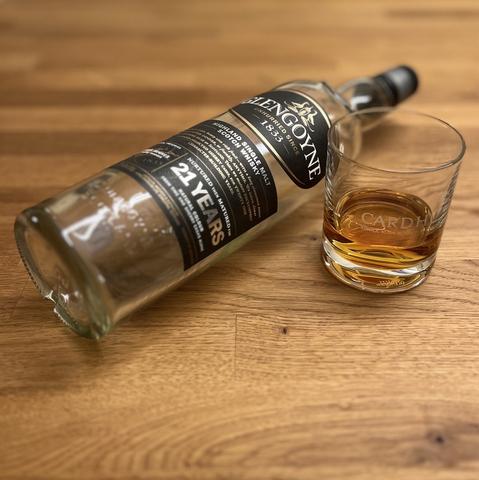 Eine liegende leere Flasche 21 Jahre alter Highland Singlemalt aus der Destille Glengoyne, dazu ein Glas mit Whisky