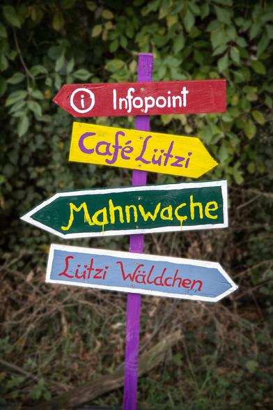 Vier bunte Hinweisschilder in Lützerath "Infopoint" "Café Lützi" "Mahnwache" "Lützi Wäldchen"
