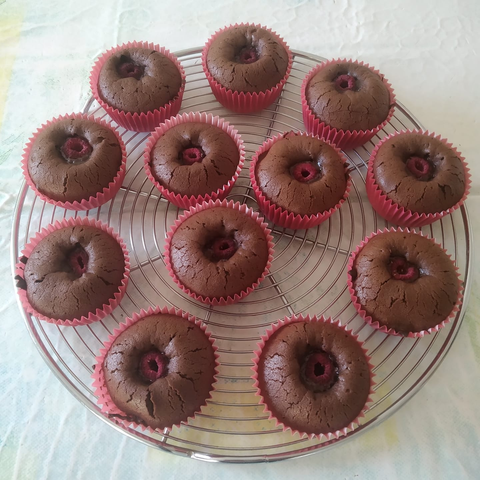 12 muffins chocolat-framboise sont disposés sur une grille ronde. Ils sont enveloppés d'un papier rose, comme les framboises