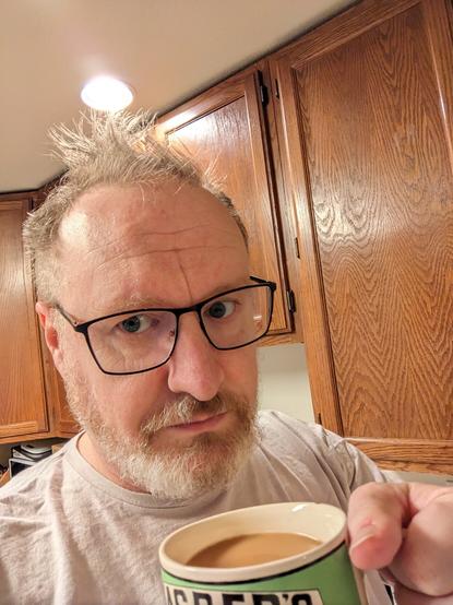 Bad hair me holding a mug of coffee