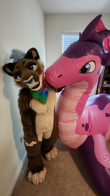 Kazi lioness fursuiter standing next to a pink and purple inflatable sea dragon.