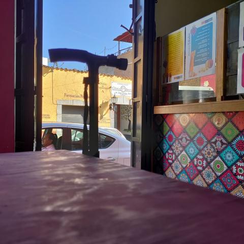 Un bastón en el umbral de una cafetería de Tepoztlán, entre una mesa de color morado y un mostrador multicolor.
