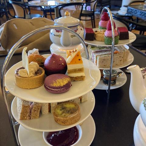 Two afternoon tea trays full of tasty treats. Some highlights are a blackberry macaron brushed with gold and some green pistachio cakes topped with pink icing and whole raspberries.

All of it was delicious.